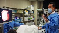 横になる患者に細い管を挿入して大腸にがんがないか調べる内視鏡検査＝関東中央病院提供