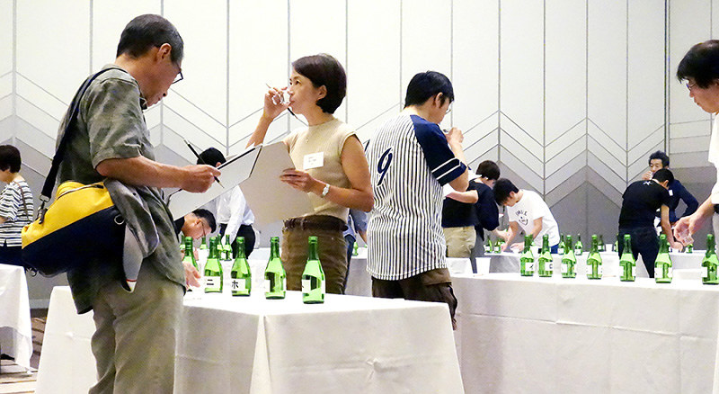 きき酒王決定戦で酒を口に含んで評価する参加者ら=大津市のびわ湖大津プリンスホテルで、濱弘明撮影