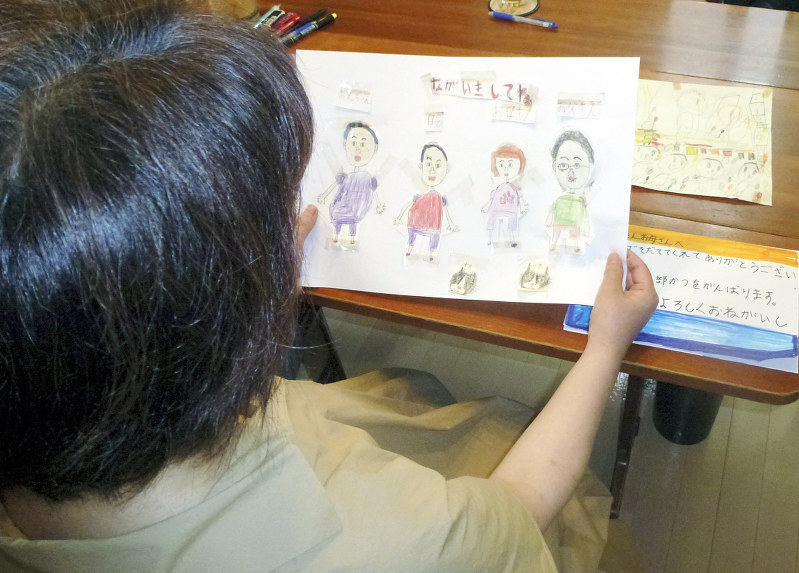 下の子が小学生の時に描いた家族の絵。「ながいきしてね」と記してある=東京都品川区で7月