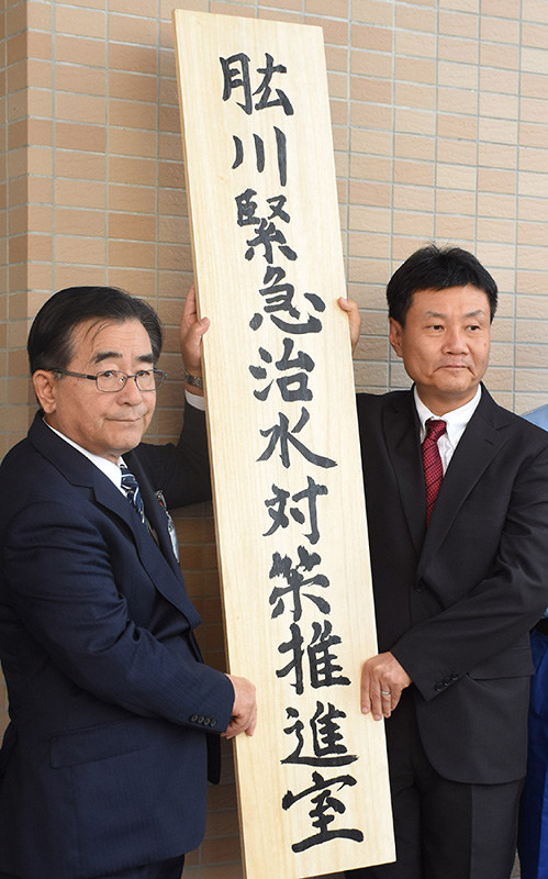 肱川緊急治水対策推進室の看板を掲げる二宮隆久・大洲市長(左)と平井秀輝・四国地方整備局長=愛媛県大洲市中村の国土交通省四国地方整備局大洲河川国道事務所で、中川祐一撮影