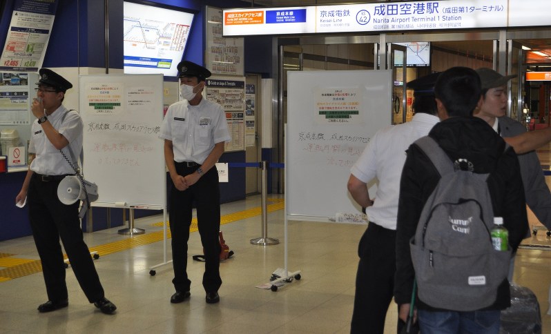 マイクを使って運転見合わせについて説明し、「ご迷惑をおかけします」と話す駅員=千葉県成田市の京成電鉄成田空港駅で2018年10月5日午後0時15分、中村宰和撮影