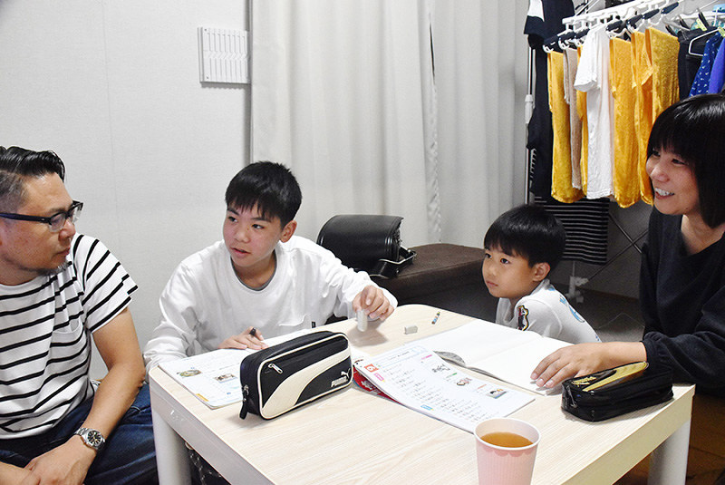 仮設住宅に入居した梶真人さん(左端)の一家。一つしかないテーブルは食卓にもなり、子どもたちの勉強机にもなる=岡山県倉敷市真備町箭田で、戸田紗友莉撮影