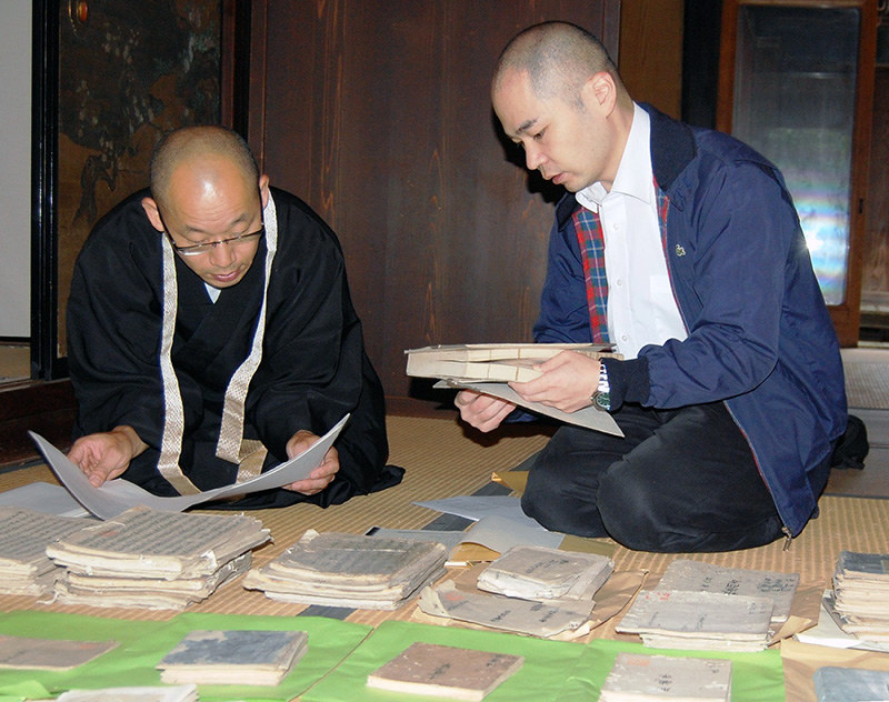 宇代貴文・学芸員(右)に古文書の説明をする教林坊の廣部光信住職=滋賀県東近江市五個荘竜田町の古民家で、蓮見新也撮影