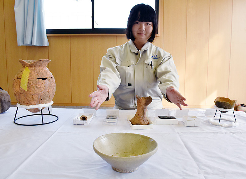 出土した白磁碗(手前)を紹介する下木千佳さん=高知県南国市で、松原由佳撮影