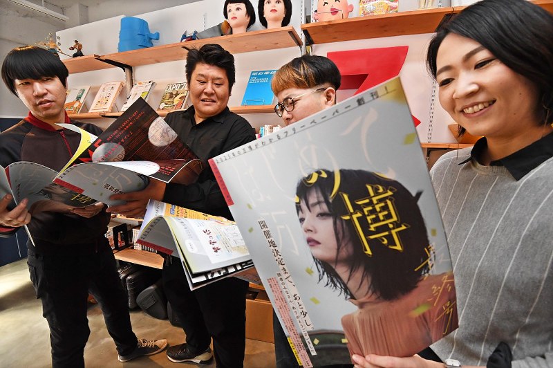 出来上がったフリーペーパー「はじめて万博」を読む吉田貴紀さん(左から2人目)ら=大阪市西区で、山崎一輝撮影