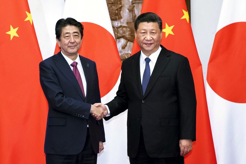 会談を前に握手する安倍首相(左)と中国の習近平国家主席=26日、AP