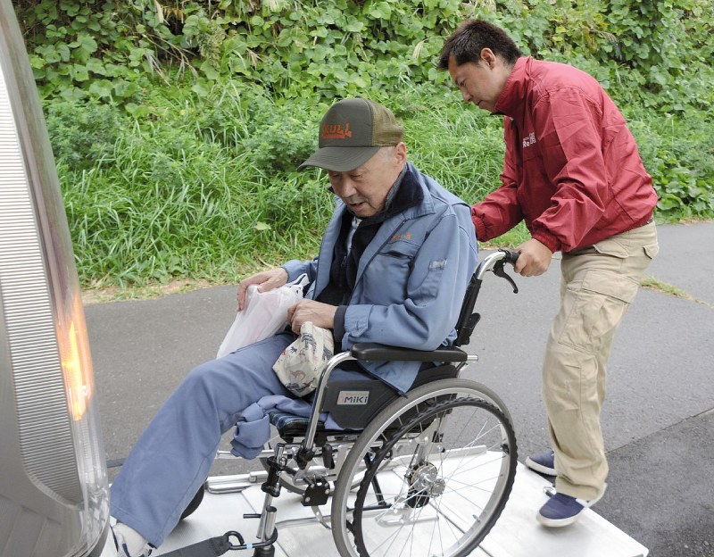 車いすの利用者を安全に車から降ろすレラの男性メンバー(右)=宮城県石巻市で、本橋敦子撮影
