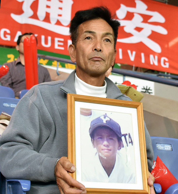 長男郁也さんの写真を手にスタンドで試合を見守る笹森義幸さん=大阪市西区の京セラドーム大阪で2018年11月4日、田崎春菜撮影