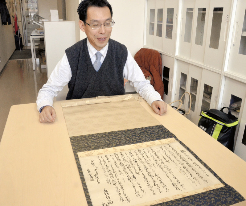 掛け軸に表装された敬白天罰霊社起請文前書と高尾善希・准教授=三重県伊賀市の三重大学国際忍者研究センターで2018年11月6日、大西康裕撮影