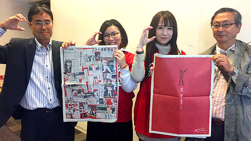黒田博樹さんが自費で中国新聞に掲載した新井貴浩選手をたたえる広告を掲げるカープファンら=東京都中央区で2018年11月6日、岡本同世撮影