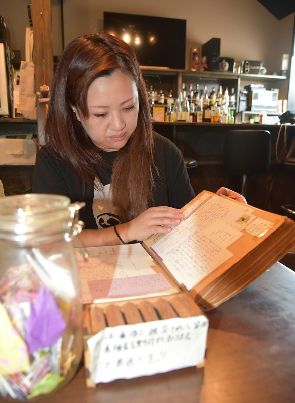 ノートに貼り付けたリアルアイの仲間たちからの激励の手紙を読み返す高橋一枝さん=宮城県女川町のバー「OWL」で