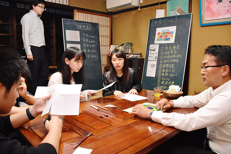 ゲームを通じて貿易について考える学生と日産プリンス滋賀販売の小林勝史さん(右)=大津市瀬田の就活スペース「tugumi」で、小西雄介撮影