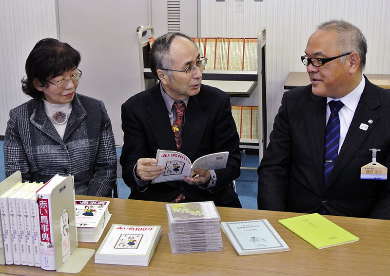 寄贈した多胡羊歯の書籍について説明する向井嘉之さん(中央)=富山県氷見市本町の市立図書館で、青山郁子撮影