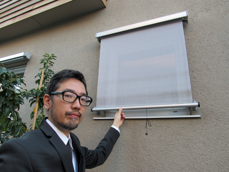 モデルハウスを案内する今泉太爾さん。屋外にあるブラインドは、夏の断熱に効果的という