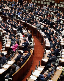 参院本会議で特定秘密保護法が可決・成立し、野党議員（手前）がぶぜんとする中、拍手する与党議員（奥）ら＝２０１３年１２月６日、森田剛史撮影