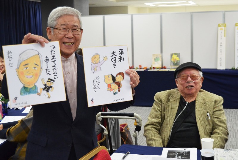 西山さん(右)から色紙をもらい、笑顔を見せる杉林さん=福岡市で