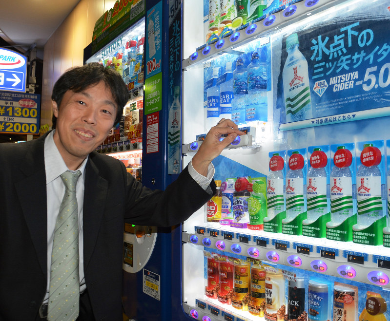 自動販売機の前で笑顔を見せる野村誠さん=東京都豊島区で、小野まなみ撮影