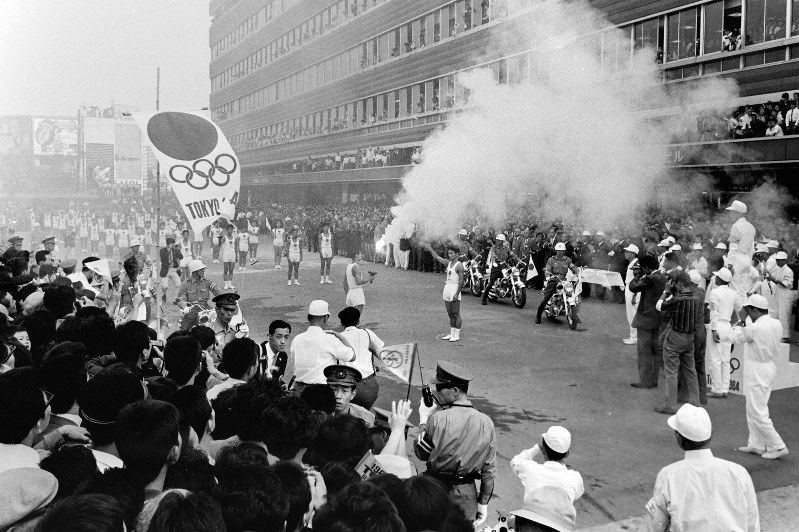 前回の東京五輪で、大勢の市民が待つ大阪市天王寺区の中継地点に到着した聖火。一路、和歌山市を目指す=1964年9月26日、橋本紀一撮影