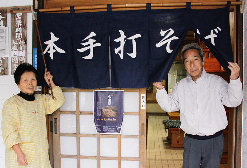 再開を前に、改めてのれんを掛ける安原よしのさん(左)と安達良一さん=養父市高中地区で、松田学撮影