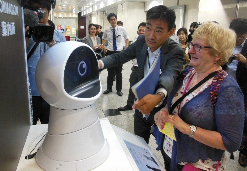 AI技術を活用したロボットに観光地への行く先を尋ねる外国人(右端)=大阪市北区のJR大阪駅で2018年10月2日、山下貴史撮影
