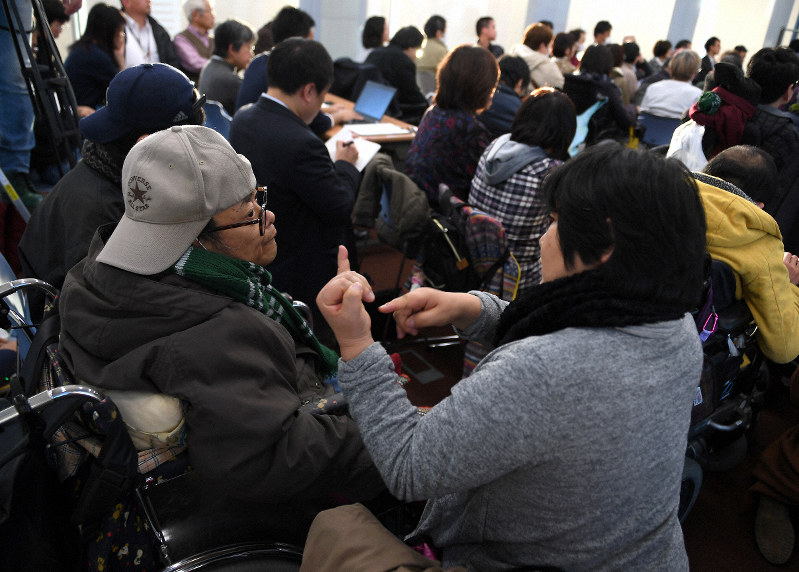 裁判後の報告集会で、弁護団の話を手話で説明される男性(手前左)=大阪市北区で2018年12月12日午後4時9分、久保玲撮影