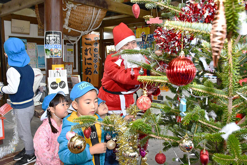 サンタさんと飾り付けをする園児たち=高知県黒潮町入野の土佐くろしお鉄道土佐入野駅で、上野力撮影