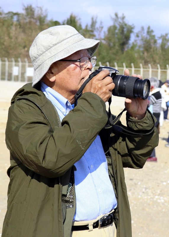 海で抗議活動を繰り広げるカヌー隊にカメラを向ける石川文洋さん=沖縄県名護市辺野古で14日