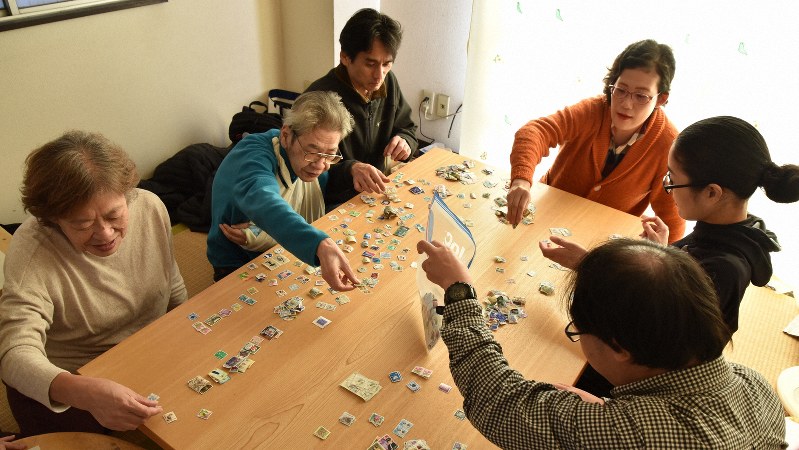 「キーベース」で使用済み切手の仕分けをする今宮眞幸さん(左から2人目)=筆者撮影