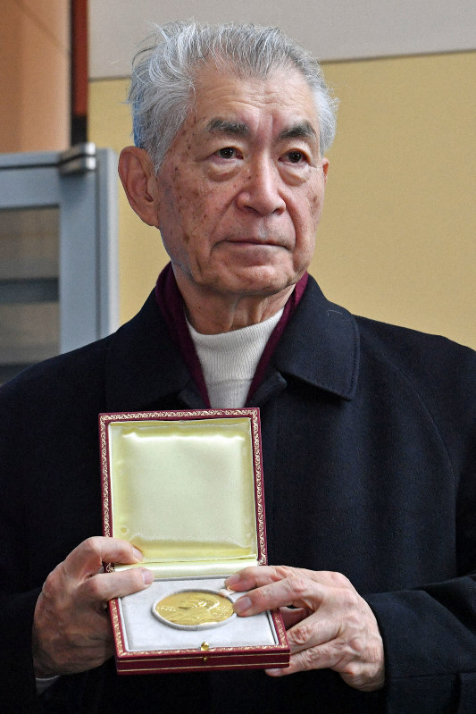 ノーベル賞授賞式から帰国し、報道陣にノメダルを披露する本庶佑・京都大特別教授=関西国際空港で2018年12月14日
