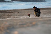 東日本大震災から７年。日の出とともに荒浜地区の海岸を訪れ、花を手向ける男性＝仙台市若林区で２０１８年３月１１日午前６時１３分、喜屋武真之介撮影
