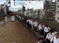 大阪北部地震。止まった電車から線路を使って移動する乗客＝大阪市福島区で２０１８年６月１８日午前９時１３分、加古信志撮影
