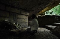 健児の塔の下のガマで手を合わせる男性＝沖縄県糸満市で２０１８年６月２３日午前８時２８分、津村豊和撮影