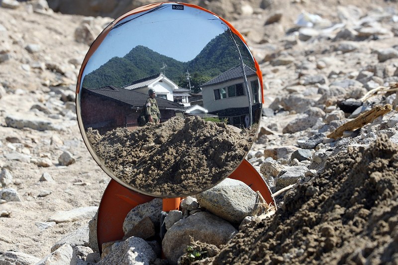 西日本豪雨。土砂に埋もれたカーブミラーにうつる自衛隊員＝広島県呉市で２０１８年７月１４日、小川昌宏撮影