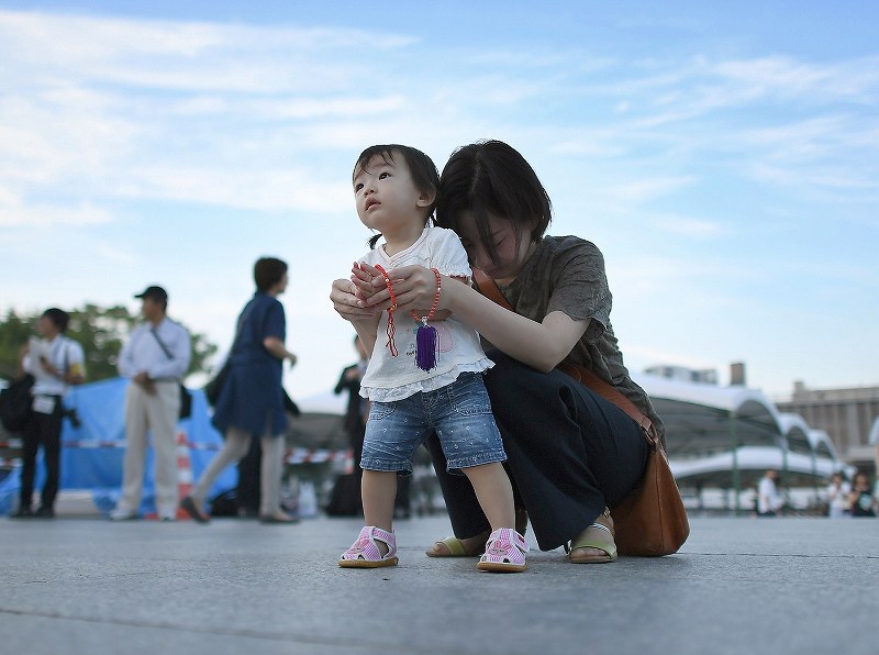 １歳になる長女と一緒に原爆慰霊碑に向かって手を合わせる女性。祖母が被爆し、女性自身も幼い時からに毎年訪れているという。「これからも一緒に来続けていきたい」＝広島市中区の平和記念公園で２０１８年８月６日午前５時３７分、久保玲撮影