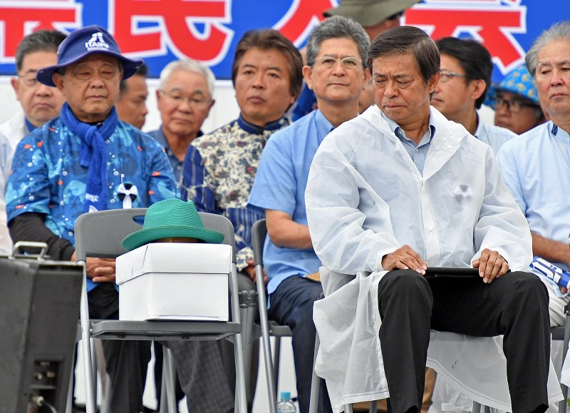 県民大会で翁長知事が被るはずだった帽子（前列左）を見つめる謝花喜一郎副知事（同右）＝那覇市で２０１８年８月１１日午前１１時９分、野田武撮影