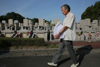 家族や親戚と霊園を訪れ、熊本地震で亡くなった河添由実さんの遺骨を運ぶ父敏明さん。敏明さん一家は地震後ずっと家の仏壇の横に置いていた由実さんの遺骨を、盆が明けたら納骨すると決心した。「近くにいてほしいという気持ちはまだあるばってん、由実も安らかに眠ってもらうごつ」＝熊本県益城町で２０１８年８月１９日午前８時４分、和田大典撮影