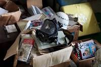 オウム真理教の教団施設から回収され、富士ケ嶺公民館の一室に置かれたままになっているガスマスクやサンスクリット語が書かれた座布団、松本智津夫元死刑囚の写真が表紙の書籍など＝山梨県河口湖町で２０１８年９月６日、小川昌宏撮影