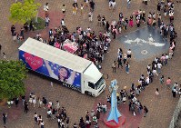 ライブ会場近くに置かれた安室奈美恵さんの顔がプリントされたトラックの周りに集まる大勢のファンら＝沖縄県宜野湾市で２０１８年９月１５日午後５時３８分、本社ヘリから森園道子撮影