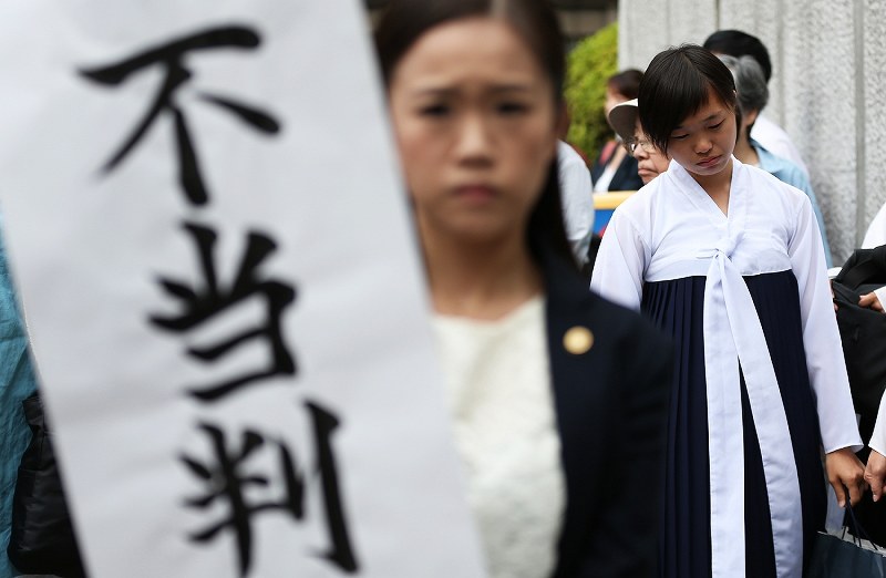 垂れ幕を掲げる弁護士の後ろで肩を落とす大阪朝鮮高級学校の生徒たち＝大阪市北区の大阪高裁前で２０１８年９月２７日午後３時６分、小出洋平撮影