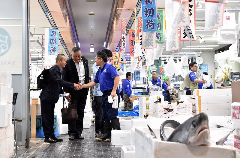 開場した豊洲市場の水産仲卸売場で、顧客の男性と笑顔で握手を交わす「山治」の山崎康弘社長（右）＝東京都江東区で２０１８年１０月１１日午前７時５１分、竹内紀臣撮影