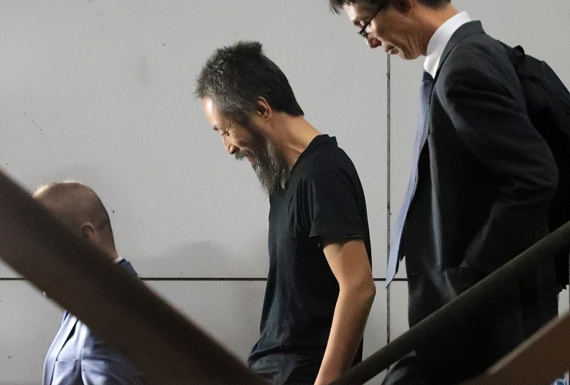 航空機から降り、階段で笑顔を見せる安田純平さん（中央）＝成田国際空港で２０１８年１０月２５日午後６時３６分、梅村直承撮影