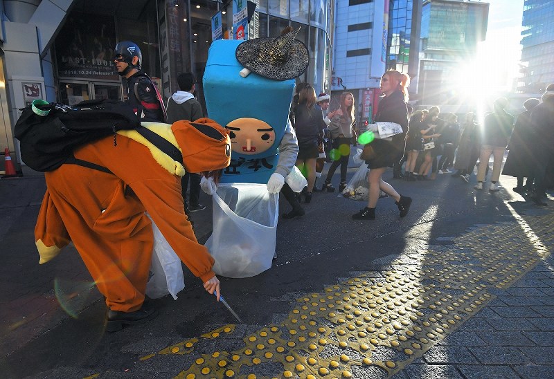 ハロウィーンから一夜明け、朝日が昇る中で仮装の姿のままゴミ拾いをする人たち＝東京都渋谷区の渋谷センター街入り口で２０１８年１１月１日午前６時５１分、手塚耕一郎撮影  