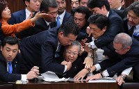 参院法務委員会で行われた入管法改正案の採決で横山信一委員長（中央）に詰め寄る議員ら＝国会内で２０１８年１２月８日午前０時２２分、渡部直樹撮影