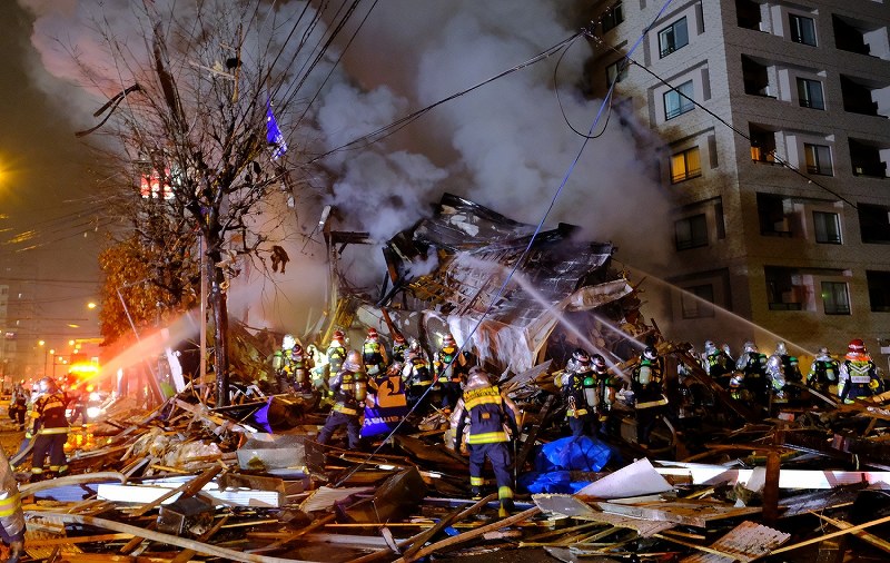 消火活動を続ける消防隊員ら。周辺には建物の残骸が散乱していた＝札幌市豊平区で2018年12月16日午後9時24分、貝塚太一撮影                
