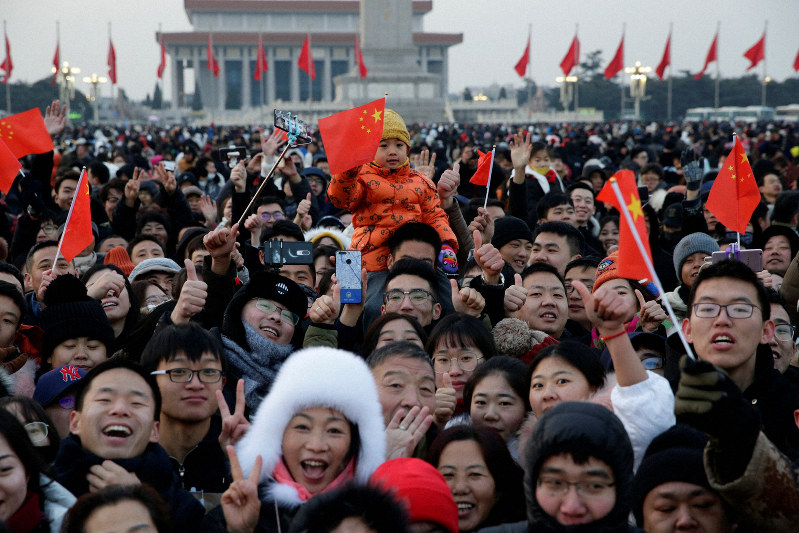 新年の国旗掲揚式典で国旗を手にする子供(中央)。中国では出生数減少が深刻化している=北京の天安門広場で1日、ロイター