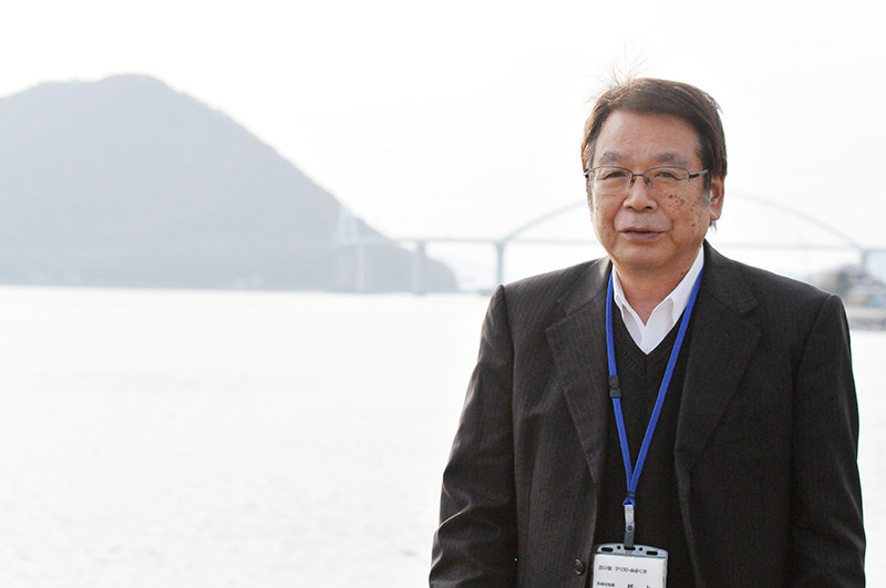 広島県福山市内海町の振興に取り組む村上設雄さん。後ろは田島(左)と沼隈半島を結ぶ内海大橋=同市沼隈町能登原で、松井勇人撮影