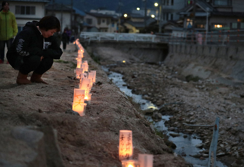 川沿いに並べられた紙灯籠を見る人たち=広島県坂町で2019年1月6日午後5時26分、小出洋平撮影