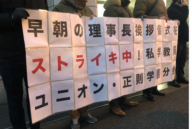 理事長への毎朝のあいさつを拒否し、横断幕を掲げて長時間労働の是正を求める正則学園高校の教員ら=東京都千代田区の同校正門前で2019年1月8日午前6時39分、森健太郎撮影