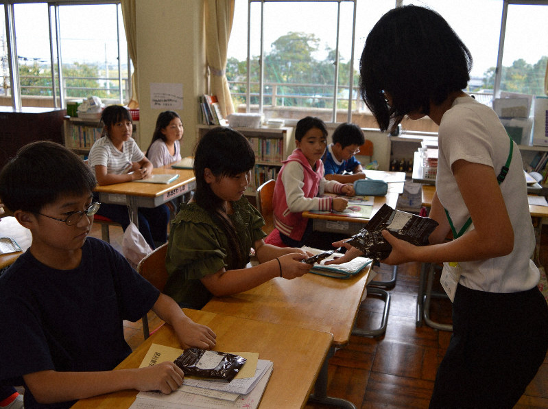 受動喫煙検診のため検尿のキットを小学4年生の児童に配る担任=埼玉県熊谷市の星宮小で2018年10月3日、斎藤義彦撮影
