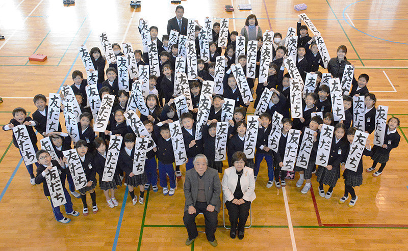 友近吾邑さん、酒井夕静さん(手前左から)を囲み、元気よく作品を掲げる3年生=愛媛県今治市黄金3の市立吹揚小で、松倉展人撮影